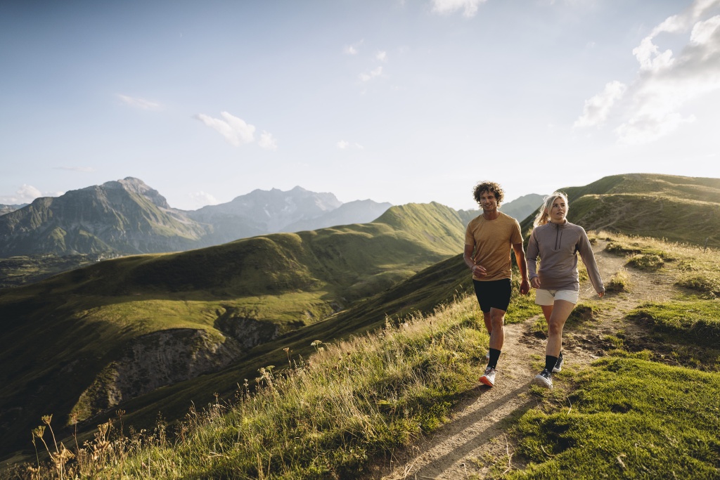 Zwei Personen wandern auf einem Pfad in den Bergen durch die Natur.